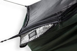 Close up photo of the corner of a green Jungle style hammock with a silver insulation pad protruding from the double layered pocket demonstrating where the pad is attached to the hammock.